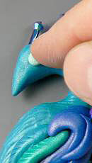 Small ball of clay being pressed into clay peacock